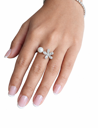Hand wearing a floral ring with a pearl on a white background