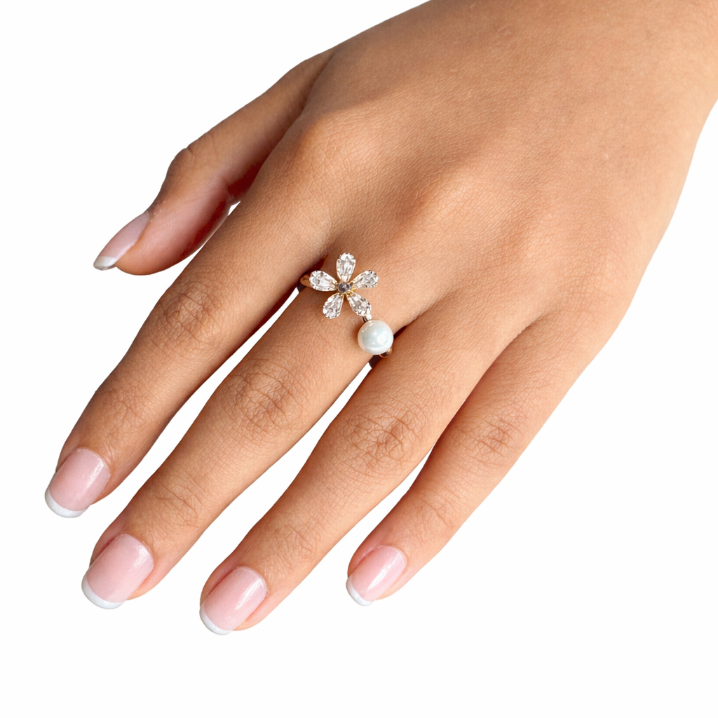 Hand wearing a decorative ring with pearls on a white background