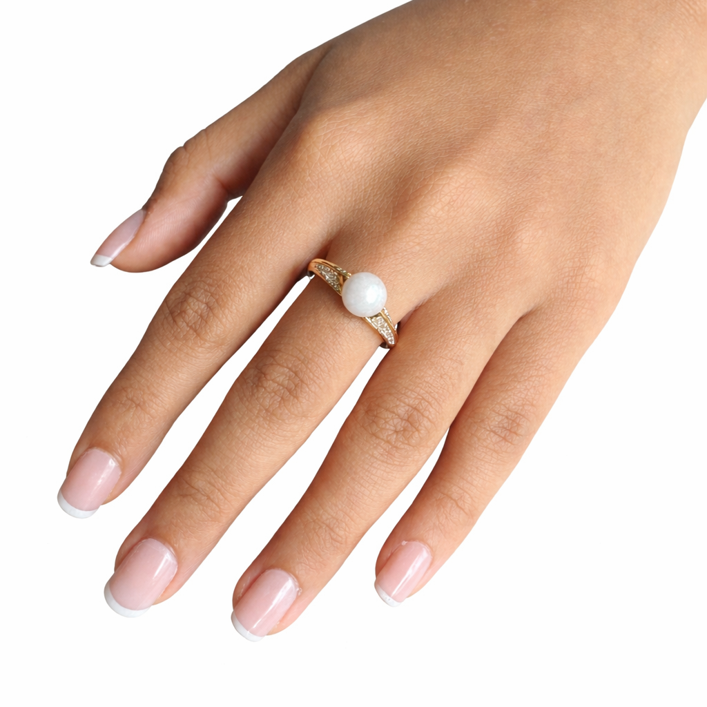 Hand wearing a ring with a white bead on a white background