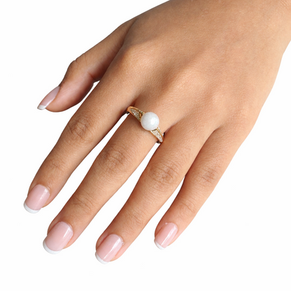 Hand wearing a ring with a white bead on a white background