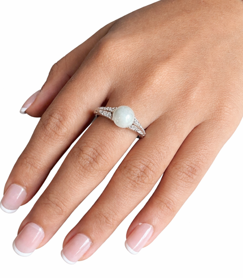 Hand wearing a ring with a pearl on a white background