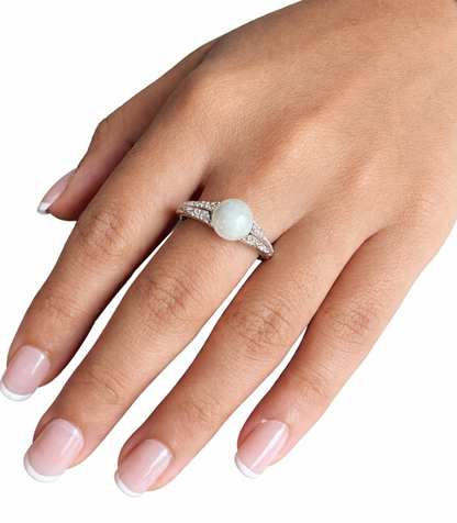 Hand wearing a ring with a pearl on a white background