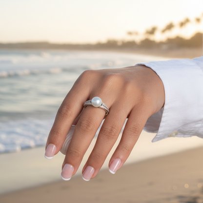 Hand wearing a ring with a pearl on a white background