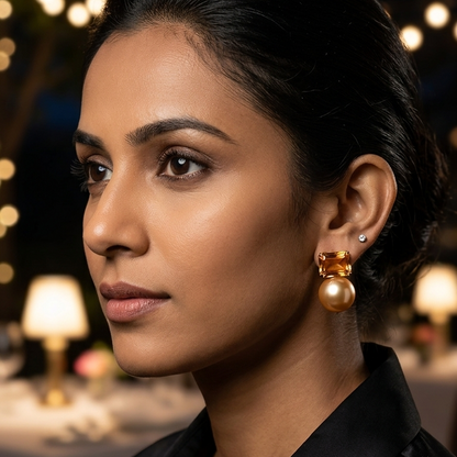Woman wearing gold earrings in a formal setting with blurred lights in the background