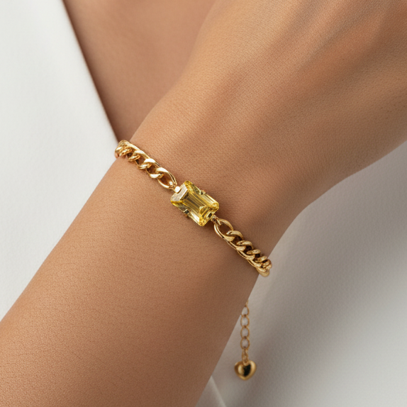 Gold bracelet with a yellow gemstone on a white background