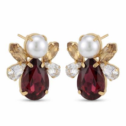 Pair of earrings with red gemstones and pearl-like centers on a white background