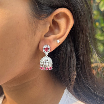 Close-up of a person wearing red and silver earrings outdoors.
