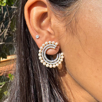 Close-up of an ear wearing a pearl earring with a blurred natural background