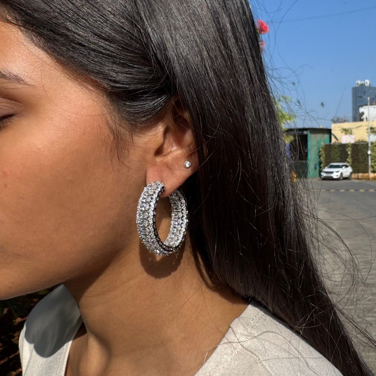 Woman wearing large hoop earrings with a cityscape in the background