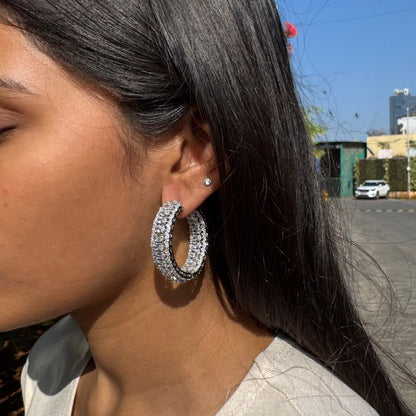 Woman wearing large hoop earrings with a cityscape in the background