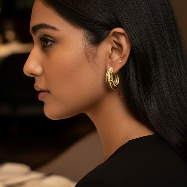 Close-up of a person wearing silver hoop earrings with a blurred natural background