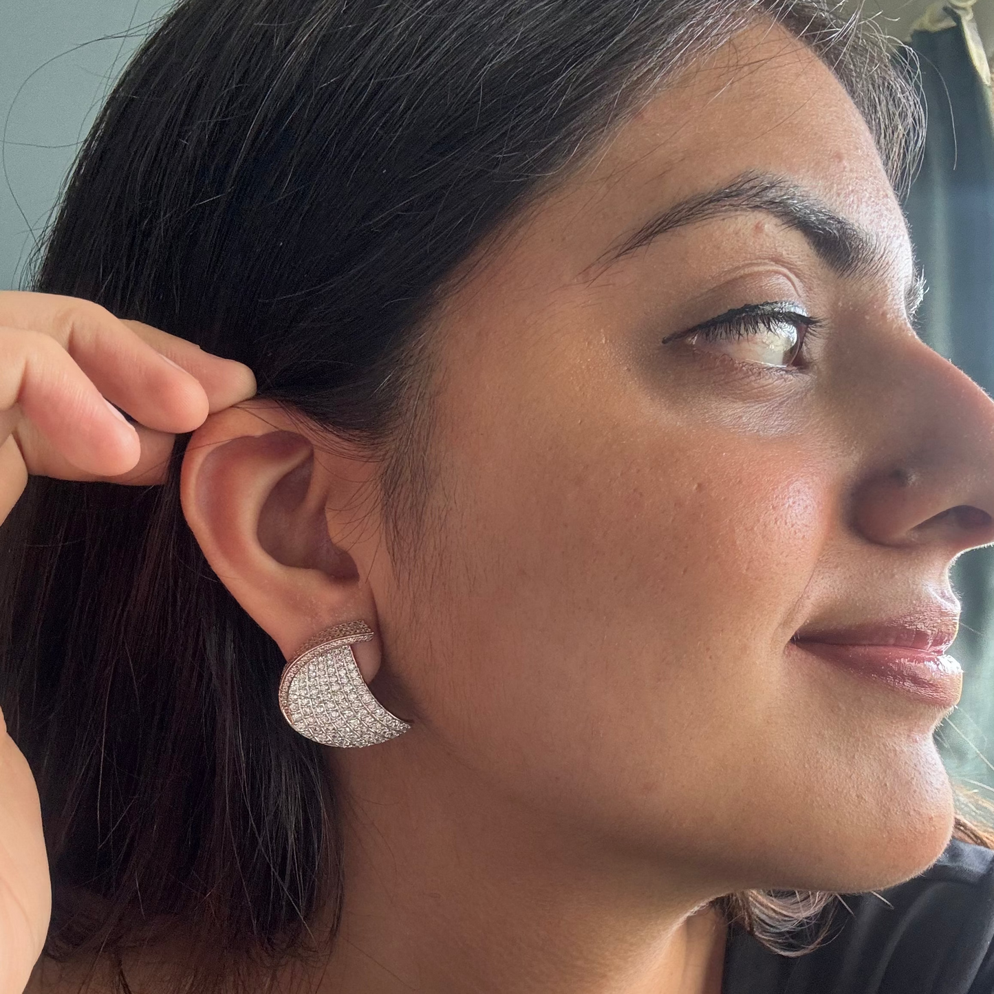Close-up of a woman wearing silver earrings with a blurred background