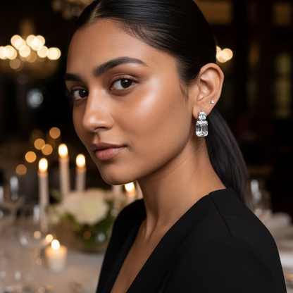 Close-up of a person wearing a silver earring with a clear gemstone.