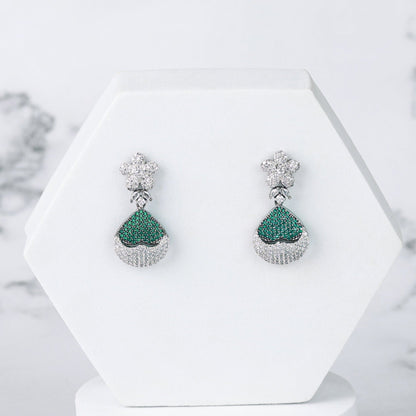 Pair of green diamond earrings on a white stand with a marble background