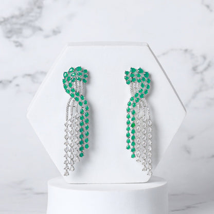 Pair of green and silver diamond earrings on a white pedestal against a marble background