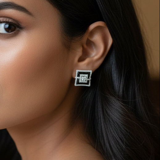 Person wearing a square earring with a logo, close-up of the ear.