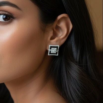 Person wearing a square earring with a logo, close-up of the ear.